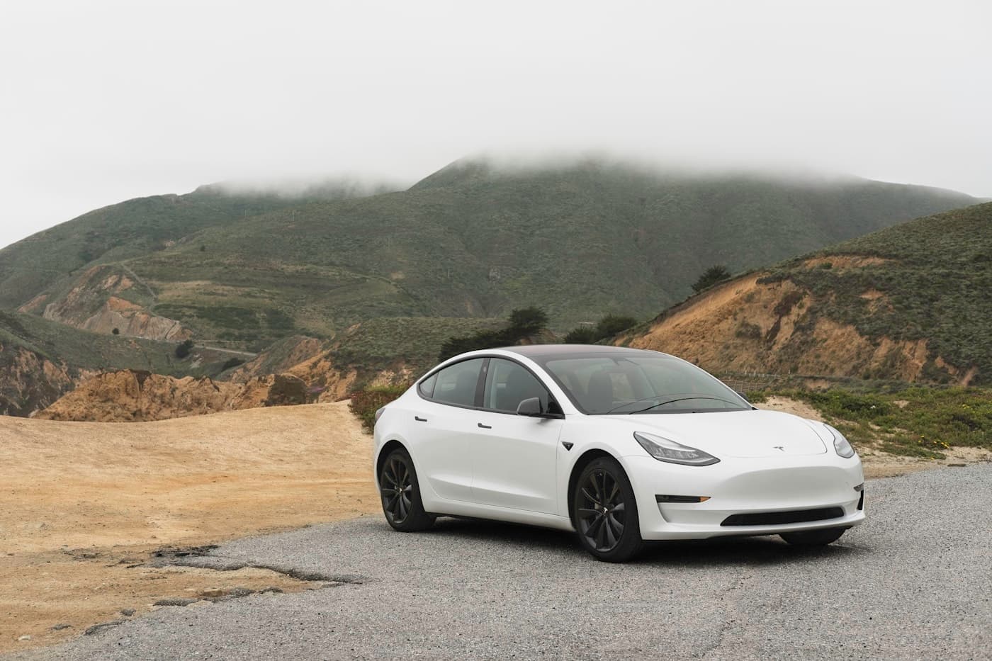 A white electric car travelling on an open road